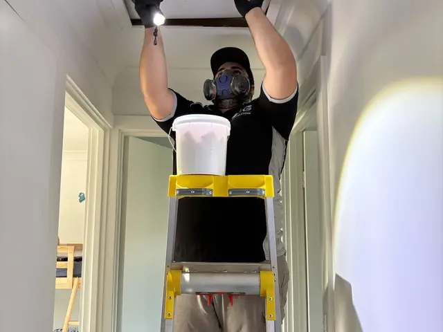 SJG technician treating a roof void through the manhole during a home pest service